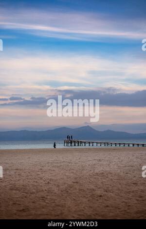 Wunderschöne Meereslandschaft bei Sonnenaufgang: Sandstrand, Meer mit hölzernem Pier, wo die Leute spazieren gehen, und im Hintergrund Berge im Morgennebel und Schönheit Stockfoto