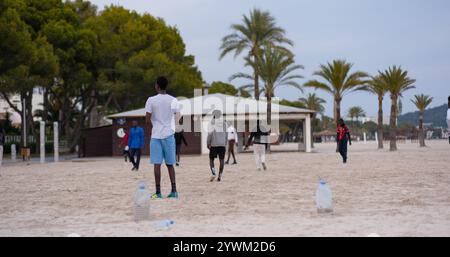 Junge Afroamerikaner spielen Fußball am Strand. Strandfußball mit improvisierten Fußballtoren aus Flaschen. Freizeit junger Männer Stockfoto