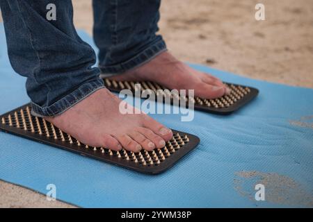 Männliche Füße stehen auf Sadhu Boards. Nahaufnahme. Das natürliche Bild eines Mannes Füße, die auf Nägeln stehen. Nagelstehend ist eine Heilpraxis für geistige und Phys Stockfoto