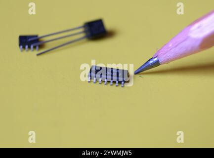 Halbleiter-IC oder integrierte Schaltung und ein Bleistift auf gelbem Hintergrund. Stockfoto