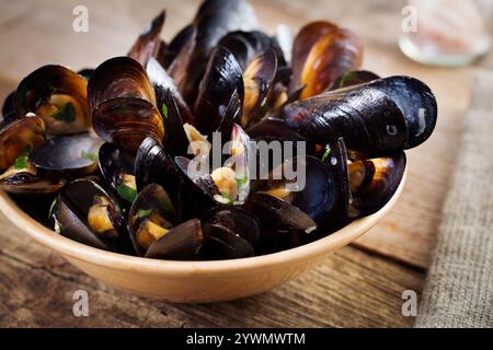 Gekochte Muscheln in Schüssel auf hölzernem Hintergrund aus nächster Nähe Stockfoto