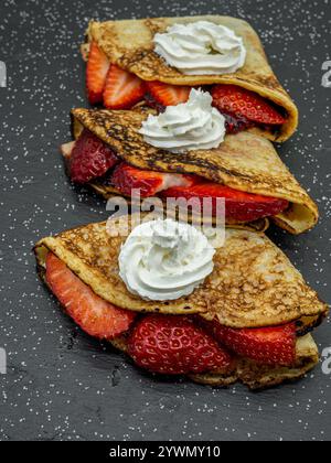 Crepes mit Erdbeere und Sahne und Schokolade auf Schieferplatte serviert Stockfoto
