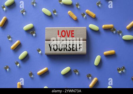 Symbol „Liebe sich selbst“. Concept Words lieben dich auf Holzblöcken. Schöner lila Hintergrund mit Pillen. Achtsamkeit und Selbstliebe. Cop Stockfoto