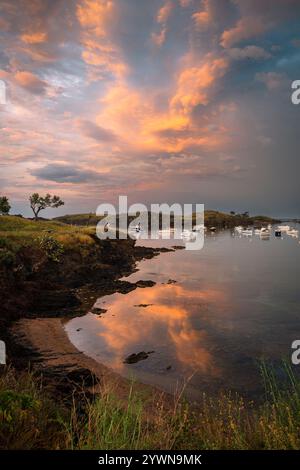 Boote ankerten in der Bucht von Portlligat unter einem dramatischen Abendhimmel bei Sonnenuntergang nach einem Gewitter, Cadaques, Katalonien, Spanien Stockfoto