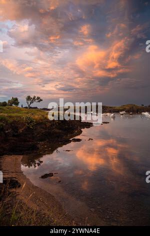 Boote ankerten in der Bucht von Portlligat unter einem dramatischen Abendhimmel bei Sonnenuntergang nach einem Gewitter, Cadaques, Katalonien, Spanien Stockfoto