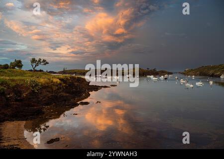 Boote ankerten in der Bucht von Portlligat unter einem dramatischen Abendhimmel bei Sonnenuntergang nach einem Gewitter, Cadaques, Katalonien, Spanien Stockfoto