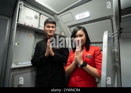 CHIANG Mai, THAILAND - 14. OKTOBER 2023: Besatzungsmitglieder in Uniform, die Wai an Bord eines AirAsia-Flugzeugs ausführen. Stockfoto