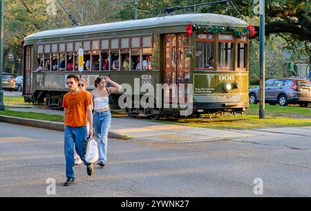 New Orleans, LA, USA - 9. Dezember 2022: Die weihnachtlich geschmückte Straßenbahn hielt an der St. Charles Avenue, in der Nähe der Universitäten und des Audubon Park, und die Passagiere gingen über die Straße Stockfoto