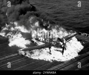 Ein abgestürzter Grumman F6F Hellcat brennt auf dem Flugdeck der USS Lexington. Das amerikanische Trägerflugzeug des Zweiten Weltkriegs feierte sein Kampfdebüt im September 1943 und etablierte sich anschließend als robuster, gut konstruierter Trägerflugzeug. In der zweiten Hälfte des Pazifikkrieges wurde sie zum dominierenden Jagdflugzeug der United States Navy. Insgesamt wurden 12.275 in etwas mehr als zwei Jahren gebaut und Hellcats wurde zugeschrieben, insgesamt 5.223 feindliche Flugzeuge zu zerstören, während sie bei der U.S. Navy, dem U.S. Marine Corps und der Royal Navy Fleet Air Arm (FAA) im Einsatz waren. Stockfoto