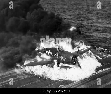 Ein abgestürzter Grumman F6F Hellcat brennt auf dem Flugdeck der USS Lexington. Das amerikanische Trägerflugzeug des Zweiten Weltkriegs feierte sein Kampfdebüt im September 1943 und etablierte sich anschließend als robuster, gut konstruierter Trägerflugzeug. In der zweiten Hälfte des Pazifikkrieges wurde sie zum dominierenden Jagdflugzeug der United States Navy. Insgesamt wurden 12.275 in etwas mehr als zwei Jahren gebaut und Hellcats wurde zugeschrieben, insgesamt 5.223 feindliche Flugzeuge zu zerstören, während sie bei der U.S. Navy, dem U.S. Marine Corps und der Royal Navy Fleet Air Arm (FAA) im Einsatz waren. Stockfoto