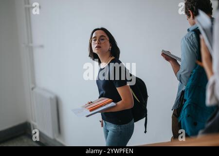 Studenten, die in einem Flur laufen und Bücher und Rucksäcke halten Stockfoto