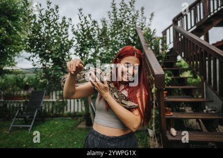Rothaariges Mädchen, das eine große Schlange im Freien hält Stockfoto