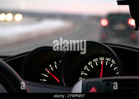 Nahaufnahme des Tachometers mit verschwommener Straße im Hintergrund. Bewegung, Geschwindigkeit und Fahrt auf einer Autobahn, Auto fahren, Auto-Armaturenbrett Stockfoto