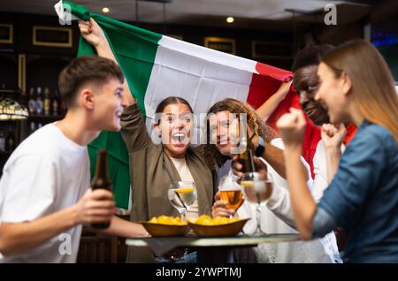 Internationale Fußballfans schwenken die italienische Flagge und unterstützen die Nationalmannschaft in der Sportbar Stockfoto