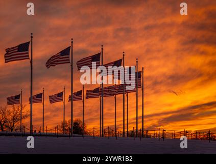 Reihen amerikanischer Flaggen, die vor einem leuchtenden orange-roten Sonnenuntergang in der Nähe des Washington Monuments stehen. Stockfoto