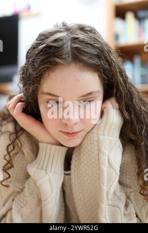 Teenager-Mädchen, das auf dem Boden liegt, mit Händen auf dem Gesicht, die Hände unter dem Kinn lockiges Haar gestützt Stockfoto