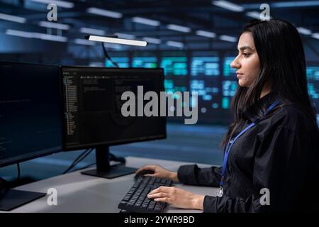 Softwareprogrammierer in der Serverfarm mit der Aufgabe, Mainframe-Geräte zu überwachen, die für die Verwaltung von Datenbanken verwendet werden. Indische Frau in Rechenzentrumseinrichtungen überprüft RackMounts, in denen Informationen gespeichert werden Stockfoto