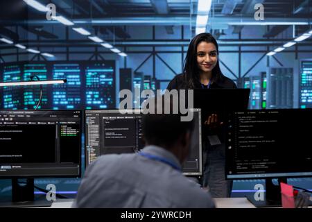 Manager beaufsichtigt Ingenieure, die auf Anzeichen eines bevorstehenden Ausfalls in Rechenzentrumsgeräten prüfen. Teamleiter, der Mitarbeiter überwacht, Schäden an Serverclustern verhindert und kritische Systeme überwacht Stockfoto