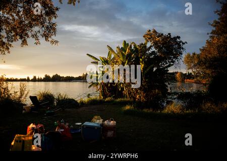 Ein Herbstpicknick mit Taschen und Körben am Mincio River in Mantua mit Angelruten am Ufer. Erfasst bei Sonnenuntergang, die s Stockfoto