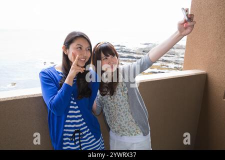 Zwei junge Frauen machen Fotos auf dem Hotelbalkon Stockfoto