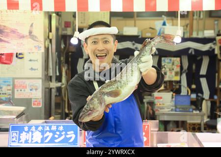 Männlicher Angestellter im Frischfischgeschäft mit Fisch Stockfoto