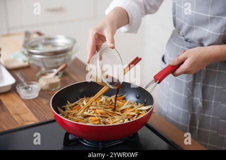 Eine Frau würzt den Kinpira Gobo Stockfoto