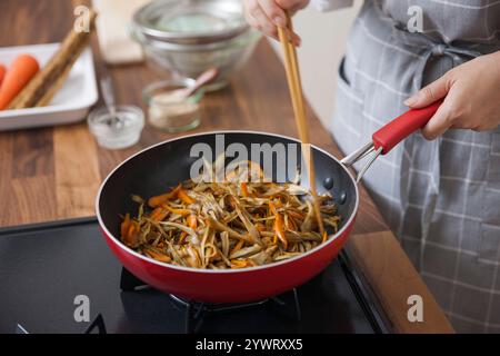 Frau, die den Kinpira-Gobo beendet Stockfoto