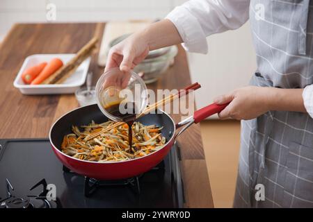 Eine Frau würzt den Kinpira Gobo Stockfoto