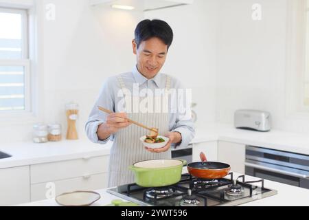 Mann mittleren Alters, der mit Schürze kocht Stockfoto