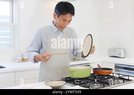 Mann mittleren Alters, der mit Schürze kocht Stockfoto