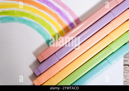 Pastellmarker und Zeichnung eines Regenbogens auf einem weißen Blatt Stockfoto