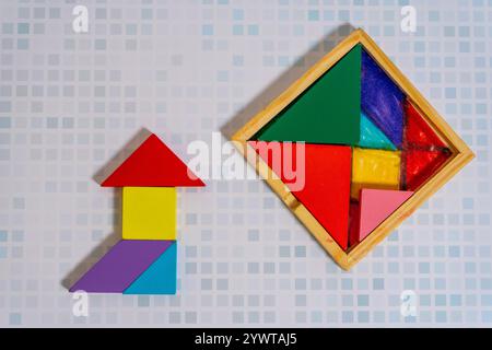 Ein farbenfrohes Tangram-Puzzle, das eine Figur mit seinem Behälter auf einem Holztisch bildet. Stockfoto