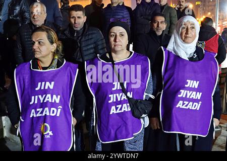 Drei kurdische Frauen, die Schürzen tragen und die Worte „Frauen, Leben, Freiheit“ tragen, bilden während der Demonstration eine Friedenskette. In Diyarbakir, Türkei, versammelten sich Hunderte kurdischer Frauen auf dem Scheich Said Platz an der Dicle Amed Women's Platform (DAKAP) und hielten Hände, um eine lange Friedenskette zu bilden. Unterstützt wurde die Demonstration von Frauen, Mitbürgerinnen von Kommunen, Vertretern kurdischer politischer Parteien und zivilgesellschaftlicher Organisationen. In den Reden auf der Demonstration forderten sie eine vollständige Beendigung des Krieges in Syrien und den Schutz der kurdischen Region Rojava. Stockfoto