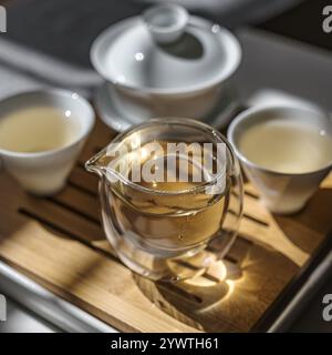Ein elegantes Teeset mit einem Tee-Infuser und Tassen auf einem Holztablett Stockfoto