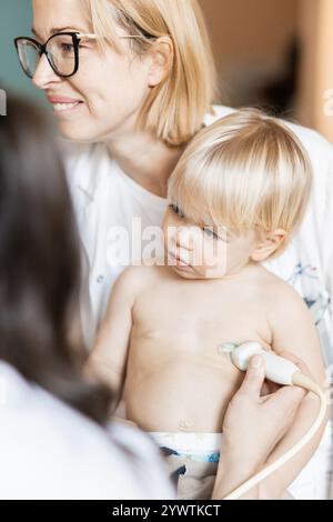 Kleinkind, das im Rahmen der regelmäßigen ärztlichen Untersuchung beim Kinderarzt durch Herzsonographie durch Kardiologen auf Herzgeräusche untersucht wird Stockfoto