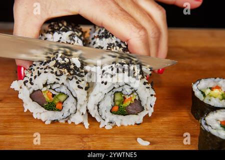 Eine vielfältige Auswahl an Sushi-Brötchen, serviert auf eleganten Tellern mit Sojasauce und Essstäbchen, schafft eine lebendige japanische Speiseszene. Stockfoto
