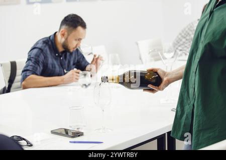 Der Barkeeper schenkt Sekt in Gläser für die Teilnehmer des Trainings in der Sommelier-Ausbildungsschule. Stockfoto