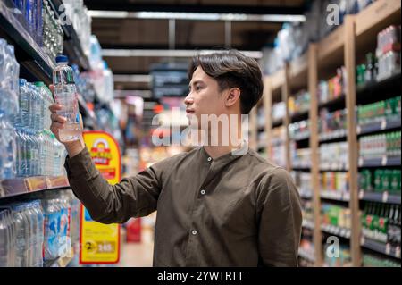 Chiang Mai, Thailand - 09. Dezember 2024: Ein gutaussehender asiatischer Mann, der in einem Supermarkt einkauft, Haushaltsartikel kauft und Produkte aus dem Regal auswählt. Nachteile Stockfoto