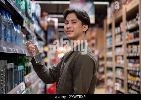 Chiang Mai, Thailand - 09. Dezember 2024: Ein gutaussehender asiatischer Mann, der in einem Supermarkt einkauft, Haushaltsartikel kauft und Produkte aus dem Regal auswählt. Nachteile Stockfoto