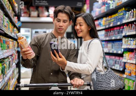Chiang Mai, Thailand - Dez 09 2024: Ein nettes junges asiatisches Paar, das zusammen in einem Supermarkt shoppt, Artikel aus den Regalen auswählt und das überprüft Stockfoto