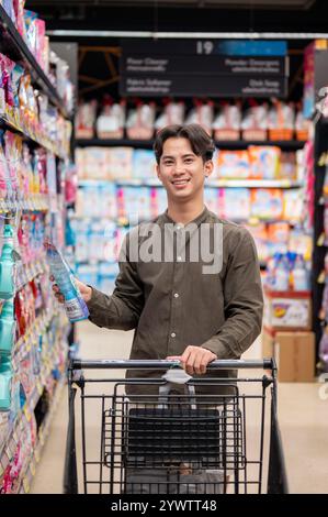 Chiang Mai, Thailand - 09. Dezember 2024: Ein gutaussehender asiatischer Mann, der in einem Supermarkt einkauft, Haushaltsartikel kauft und in die Kamera lächelt. Verbraucher, Käufer, Stockfoto