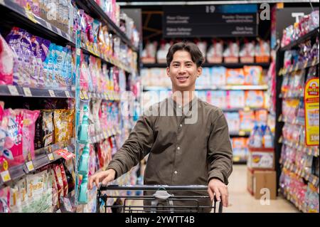 Chiang Mai, Thailand - 09. Dezember 2024: Ein gutaussehender asiatischer Mann, der in einem Supermarkt einkauft, Haushaltsartikel kauft und in die Kamera lächelt. Verbraucher, Käufer, Stockfoto