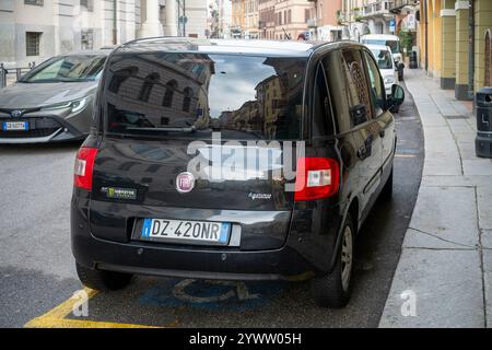 Cremona, Italien - 27. November 2024 geparkter schwarzer Fiat multipla Naturkraftwagen aus Methan, der umliegende Gebäude in einer städtischen Umgebung in italien reflektiert Stockfoto