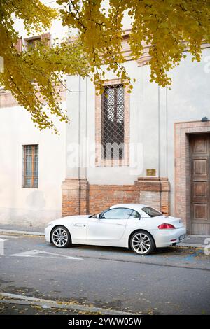 Cremona, Italien - 27. November 2024 geparkte weiße bmw z4 sdrive28i Roadster in der Nähe eines historischen Gebäudes mit gelben Herbstlaub Stockfoto