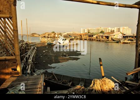 Gezeitenstrand und Stelzenhäuser im Hintergrund neuer flacher Gebäude im Küstendorf Marunda in Cilincing, Jakarta, Indonesien. Stockfoto