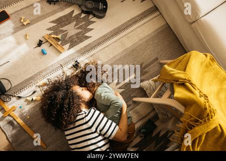 Eine Mutter küsst ihr Kind liebevoll auf einem gemütlichen Boden in einem warmen Zuhause mit Spielzeug verstreut herum. Stockfoto