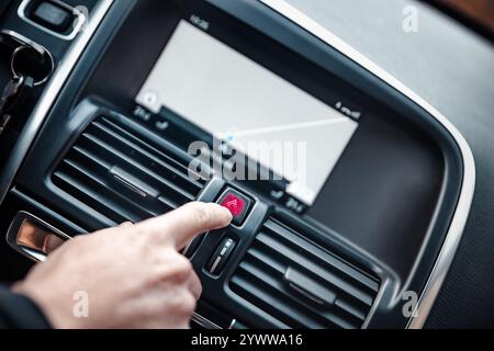 Taste der Warnblinkanlage von Hand drücken, Taste des roten Dreiecks im Fahrzeug. Warnleuchten Stockfoto