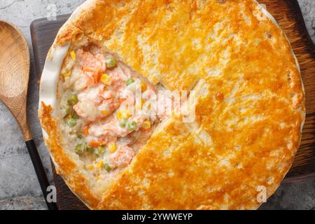 Leckere cremige Lachsgemüse Pot Pie mit knuspriger Blätterkruste auf der Auflaufform auf dem Tisch. Horizontale Draufsicht von oben Stockfoto