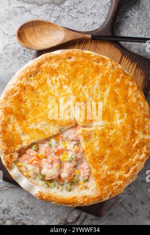 Creamy Lachse Pot Pie ist ein köstliches, einfaches und herzhaftes fest voller Aromen aus der Nähe auf der Backform auf dem Tisch. Vertikale Draufsicht von oben Stockfoto