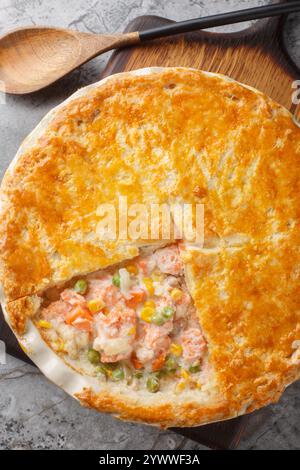 Lachs Pot Pie aus frischen Lachsfilets, gemischtem Gemüse, einer cremigen Sauce und einem knusprigen Blätterteigdeckel in der Nähe auf der Auflaufform auf der Registerkarte Stockfoto